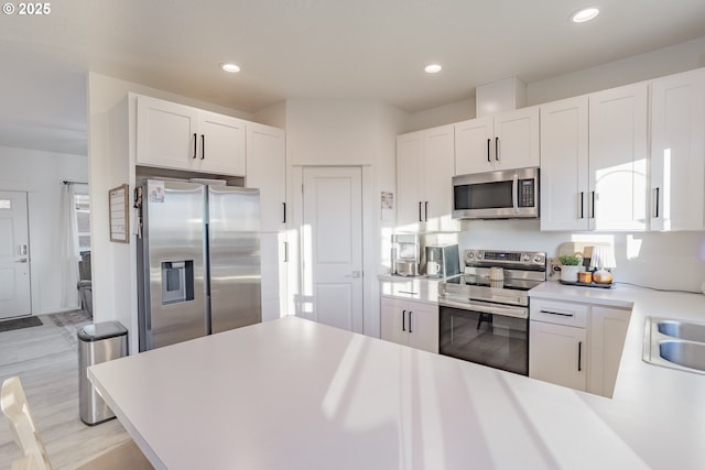 kitchen featuring sink, light hardwood / wood-style floors, white cabinets, and appliances with stainless steel finishes