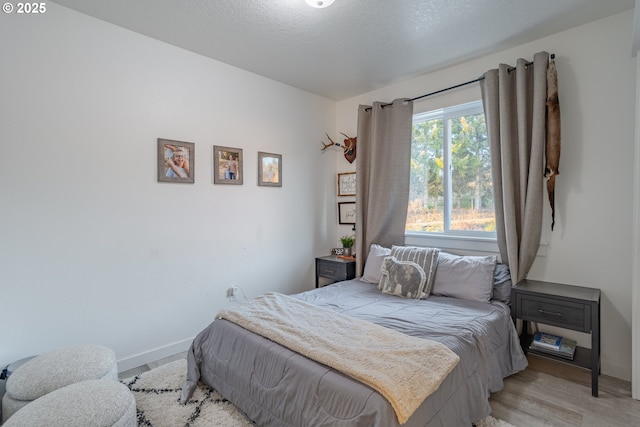 bedroom with light hardwood / wood-style floors and a textured ceiling