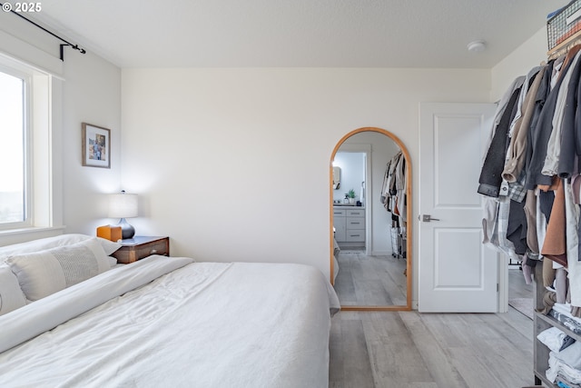 bedroom with connected bathroom and light hardwood / wood-style flooring