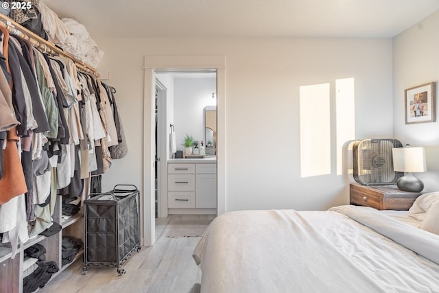 bedroom featuring connected bathroom and light wood-type flooring