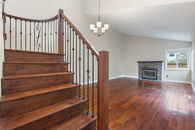 stairway with vaulted ceiling, baseboards, a fireplace with flush hearth, and hardwood / wood-style floors