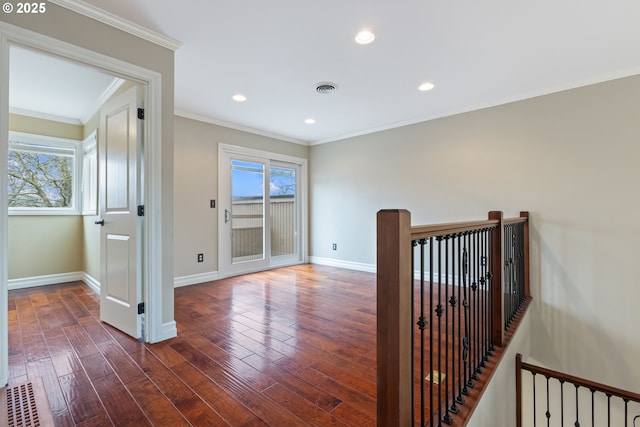 corridor with visible vents, baseboards, dark wood-style flooring, crown molding, and an upstairs landing