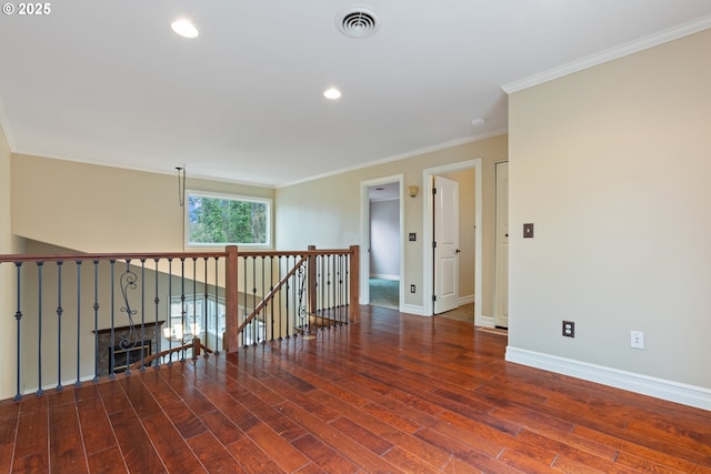 empty room with visible vents, ornamental molding, baseboards, and wood finished floors