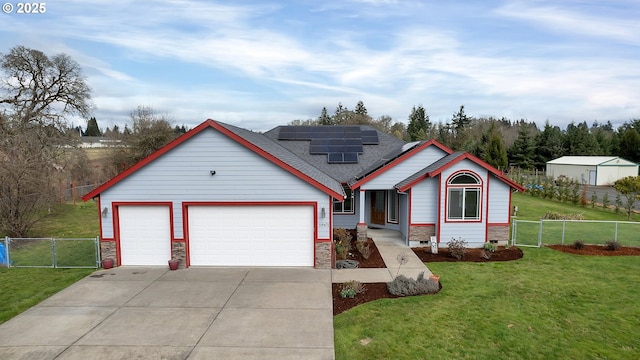 view of front of house with a front lawn, roof mounted solar panels, fence, concrete driveway, and a garage