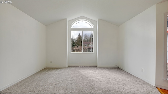 carpeted spare room with baseboards and vaulted ceiling