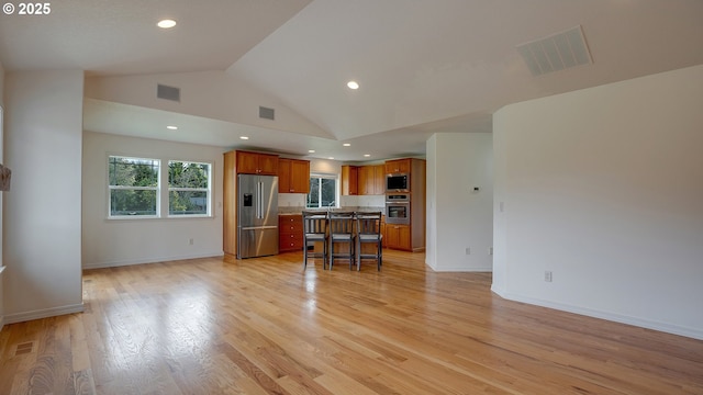 kitchen featuring stainless steel appliances, visible vents, open floor plan, and brown cabinetry