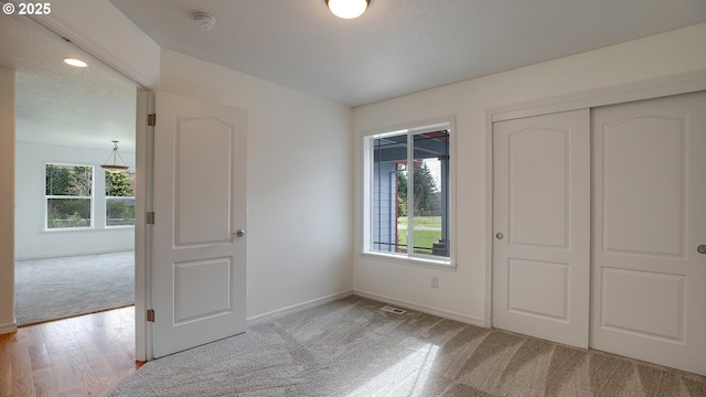 unfurnished bedroom with a closet, multiple windows, a textured ceiling, and baseboards