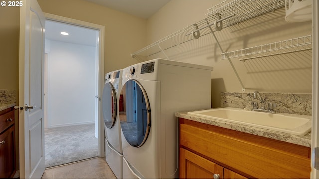 laundry room with light colored carpet, light tile patterned floors, laundry area, separate washer and dryer, and a sink