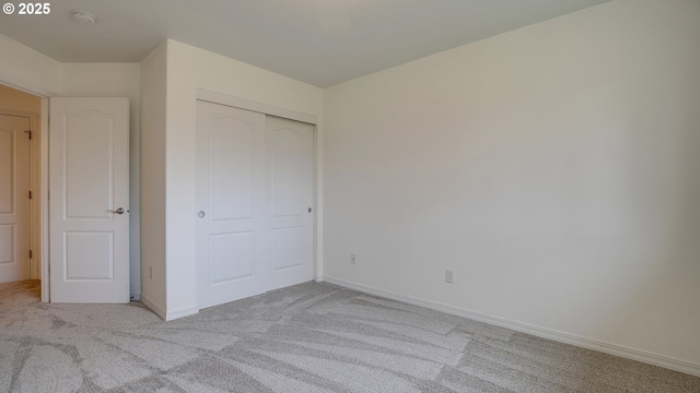 unfurnished bedroom featuring baseboards, light carpet, and a closet