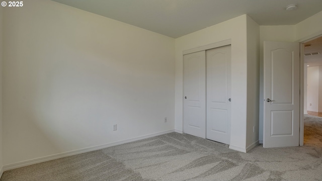 unfurnished bedroom featuring light carpet, visible vents, baseboards, and a closet