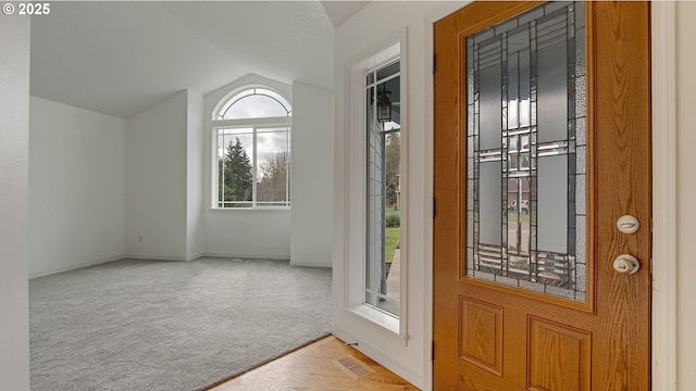 foyer entrance with visible vents, carpet floors, baseboards, and vaulted ceiling