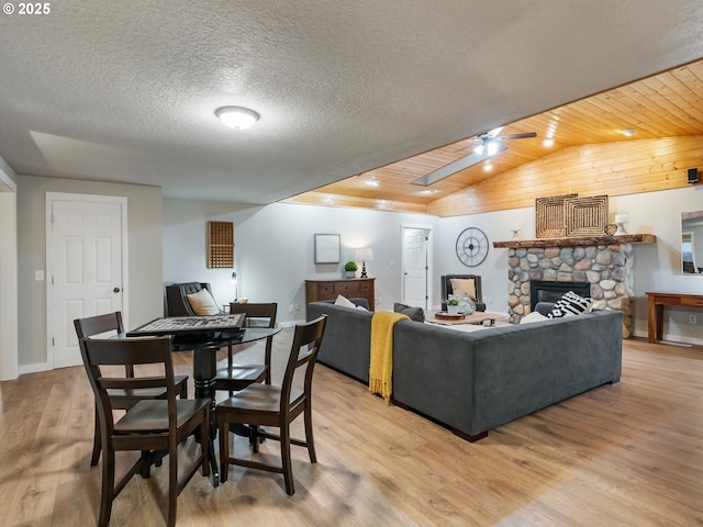 living room with a fireplace, light hardwood / wood-style flooring, ceiling fan, and wood ceiling