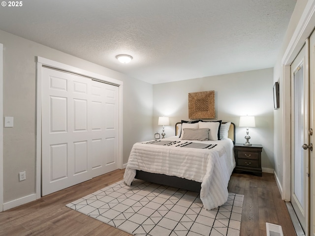 bedroom featuring a closet, a textured ceiling, and light wood-type flooring