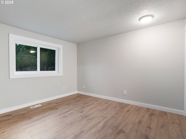 empty room featuring light hardwood / wood-style floors and a textured ceiling