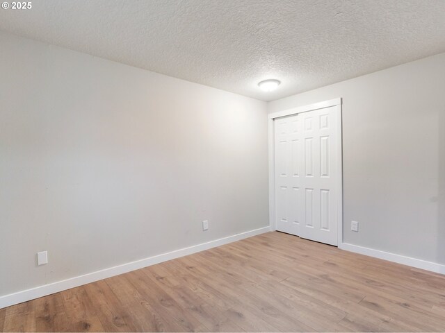 empty room featuring light wood-type flooring and a textured ceiling