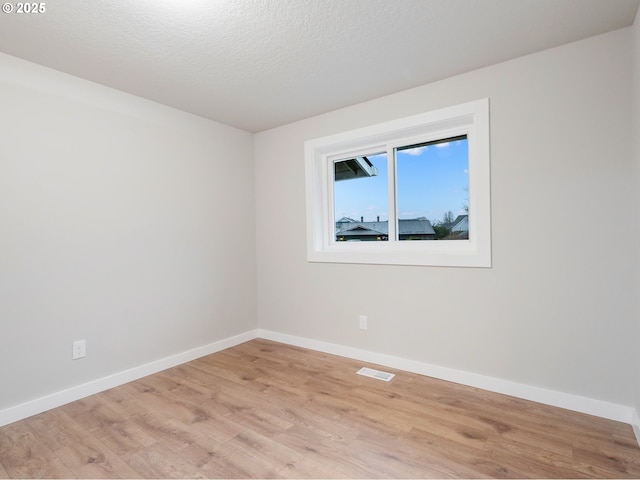 spare room featuring a textured ceiling and light hardwood / wood-style flooring