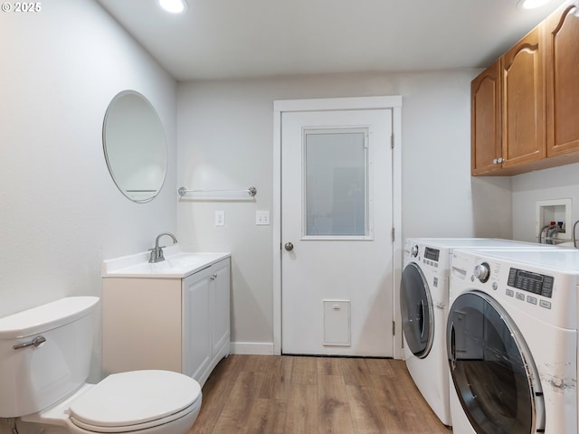 laundry area with washing machine and clothes dryer, sink, and light wood-type flooring