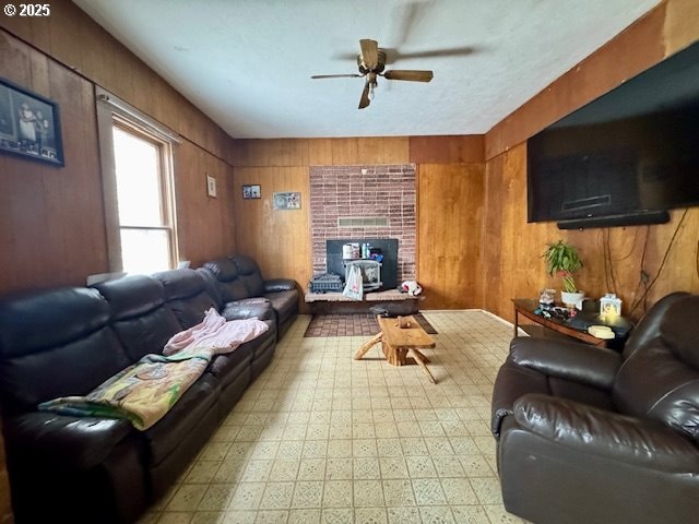 living room featuring ceiling fan, wooden walls, and tile patterned floors