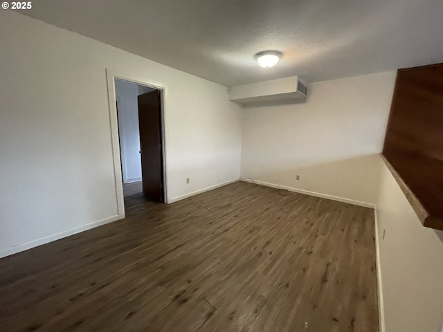 spare room featuring a textured ceiling and dark hardwood / wood-style floors