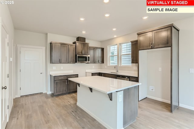 kitchen with a sink, stainless steel appliances, recessed lighting, and light wood finished floors