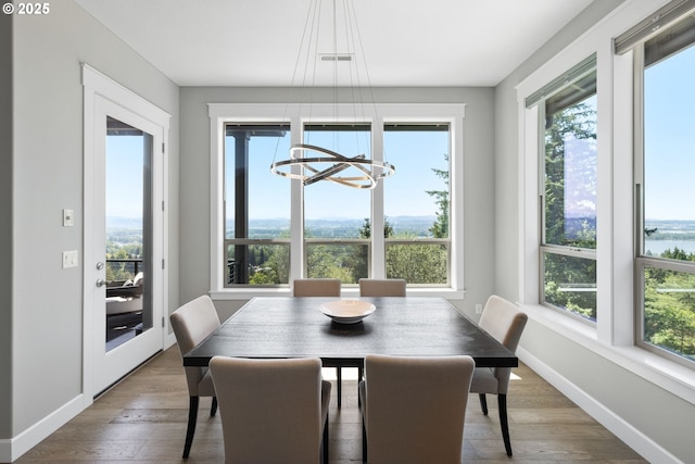 dining space with visible vents, a notable chandelier, wood finished floors, and a healthy amount of sunlight
