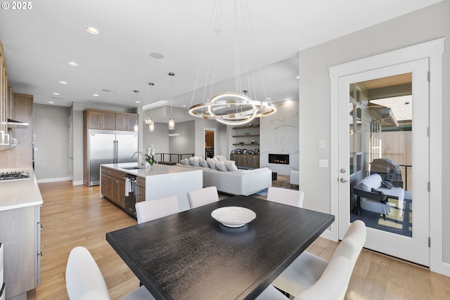 dining room with an inviting chandelier, baseboards, recessed lighting, light wood finished floors, and a premium fireplace