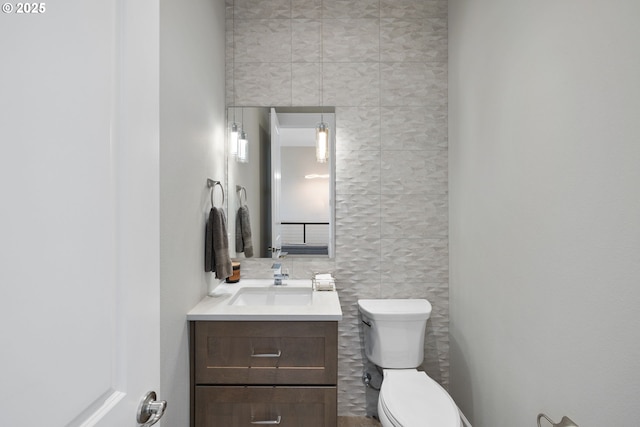 bathroom with vanity, toilet, and tile walls