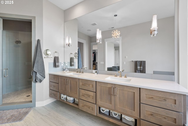full bath with a sink, a walk in closet, a shower stall, and double vanity