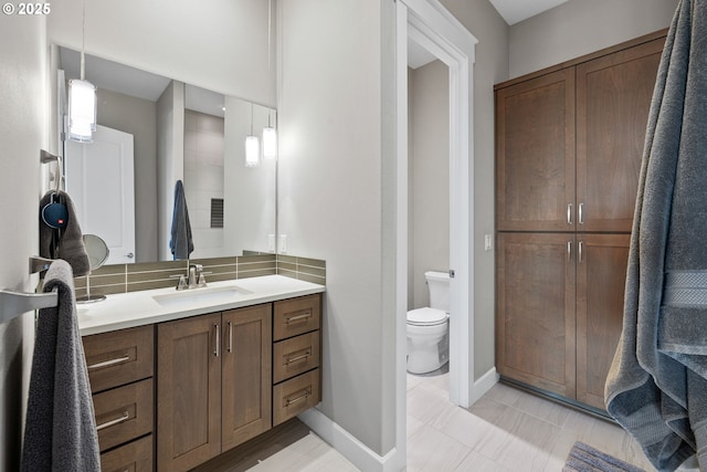 bathroom with baseboards, vanity, and toilet