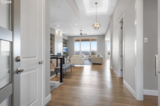 hall featuring baseboards, recessed lighting, hardwood / wood-style floors, and a raised ceiling