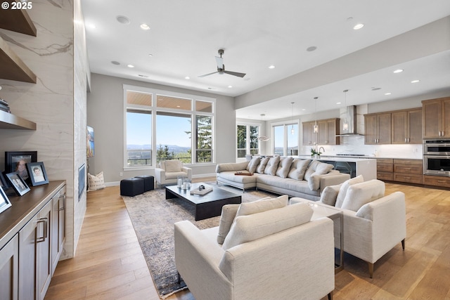 living area with baseboards, ceiling fan, light wood finished floors, and recessed lighting