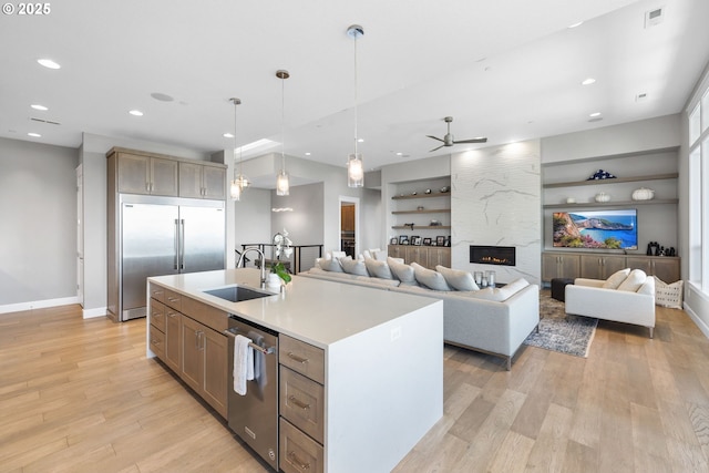 kitchen featuring appliances with stainless steel finishes, a sink, built in shelves, a ceiling fan, and baseboards