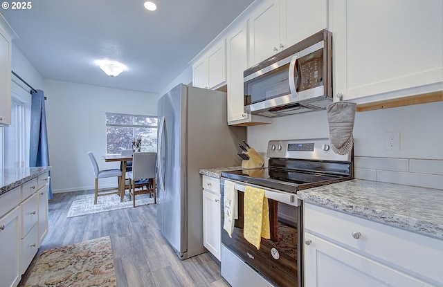 14008 SE Center St Unit A, Portland, OR 97236 - kitchen with appliances with stainless steel finishes, light wood-type flooring, white cabinetry, light stone counters, and recessed lighting