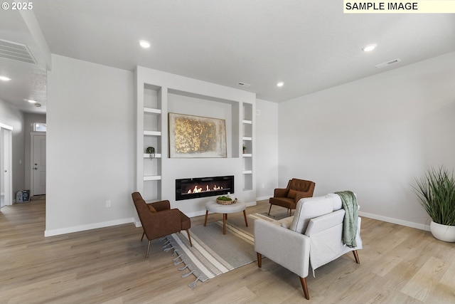 1197 NE Emerald Dr, Hermiston, OR 97838 - sitting room featuring light wood-style floors, built in shelves, a glass covered fireplace, and recessed lighting