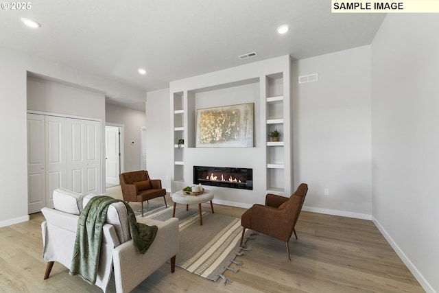 1197 NE Emerald Dr, Hermiston, OR 97838 - living area with light wood-type flooring, a glass covered fireplace, built in shelves, and recessed lighting