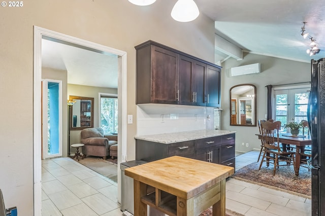 kitchen with a wall mounted AC, dark brown cabinetry, freestanding refrigerator, arched walkways, and decorative backsplash
