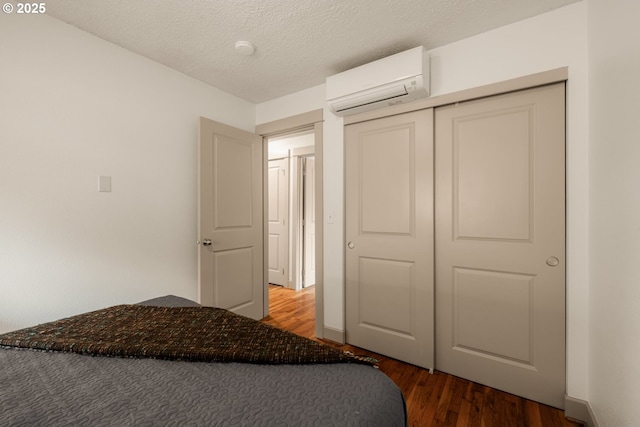 9334 N Lombard St Unit 7, Portland, OR 97203 - bedroom featuring a wall mounted air conditioner, wood finished floors, a textured ceiling, and a closet