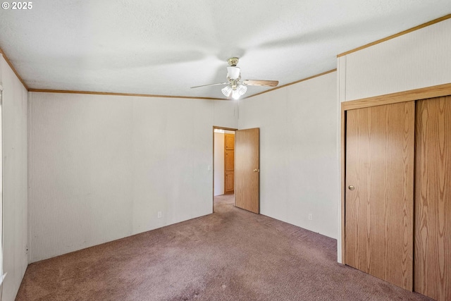 unfurnished bedroom with carpet floors, a closet, ceiling fan, and crown molding