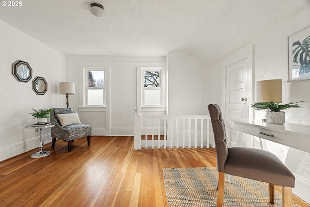 office with a textured ceiling, a textured wall, light wood-style flooring, and baseboards