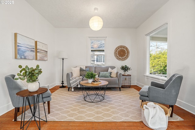 living area featuring light wood-style flooring, baseboards, and a textured ceiling