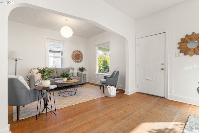 foyer with arched walkways, baseboards, and hardwood / wood-style flooring