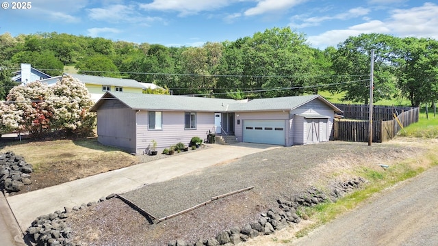 single story home featuring concrete driveway, fence, and a garage