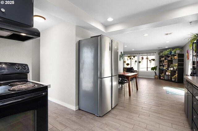 kitchen with light wood-style floors, freestanding refrigerator, visible vents, and black range with electric stovetop