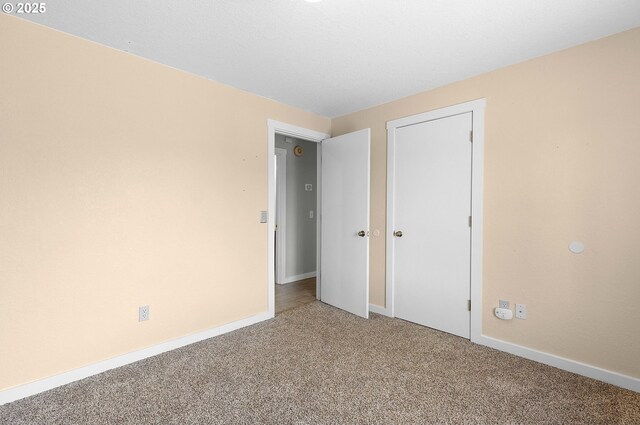 unfurnished bedroom with baseboards, carpet, and a closet