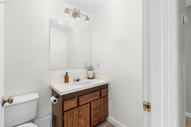 half bath with vanity, baseboards, and toilet