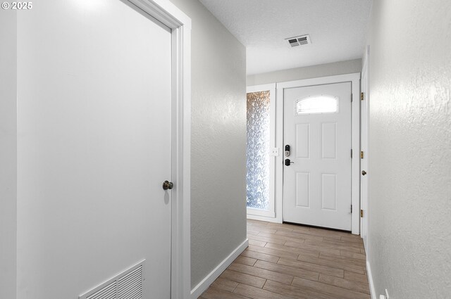 entryway with a textured wall, visible vents, and wood finished floors