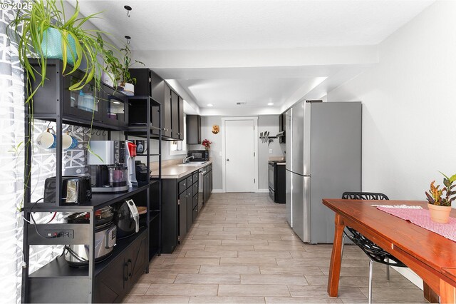 kitchen with baseboards, black appliances, light wood finished floors, dark cabinetry, and recessed lighting