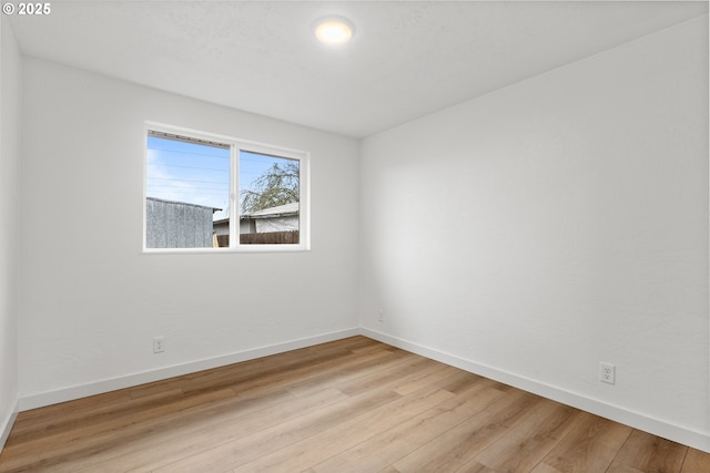 unfurnished room with light wood-type flooring and baseboards