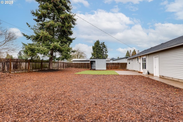 view of yard featuring a shed, a patio area, a fenced backyard, and an outdoor structure