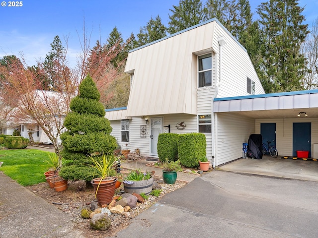 multi unit property with a carport, driveway, and metal roof